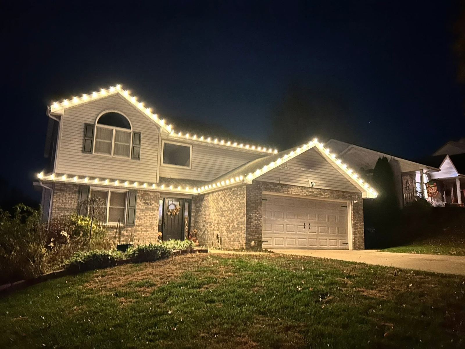 Two-story home with warm white lights at dusk